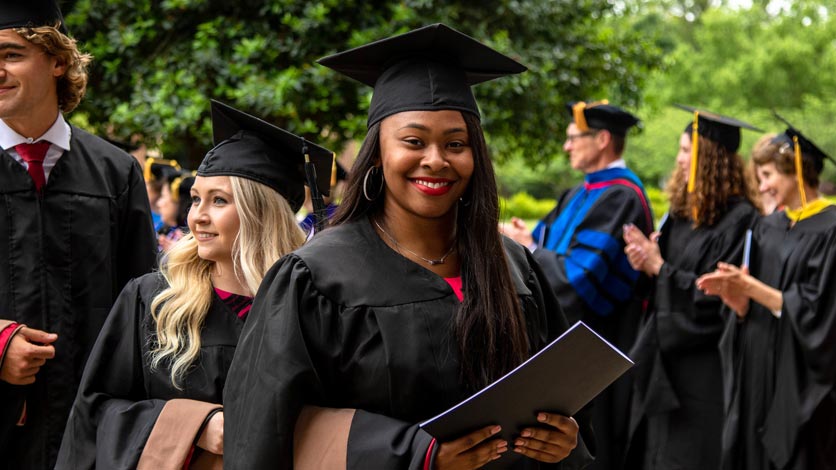 Student in audience smiles after receiving diploma at commencement