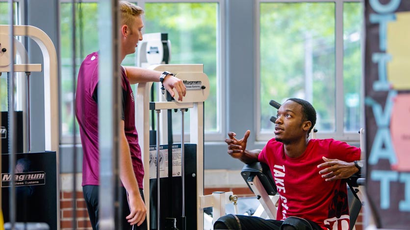Two students talking while working out in fitness center