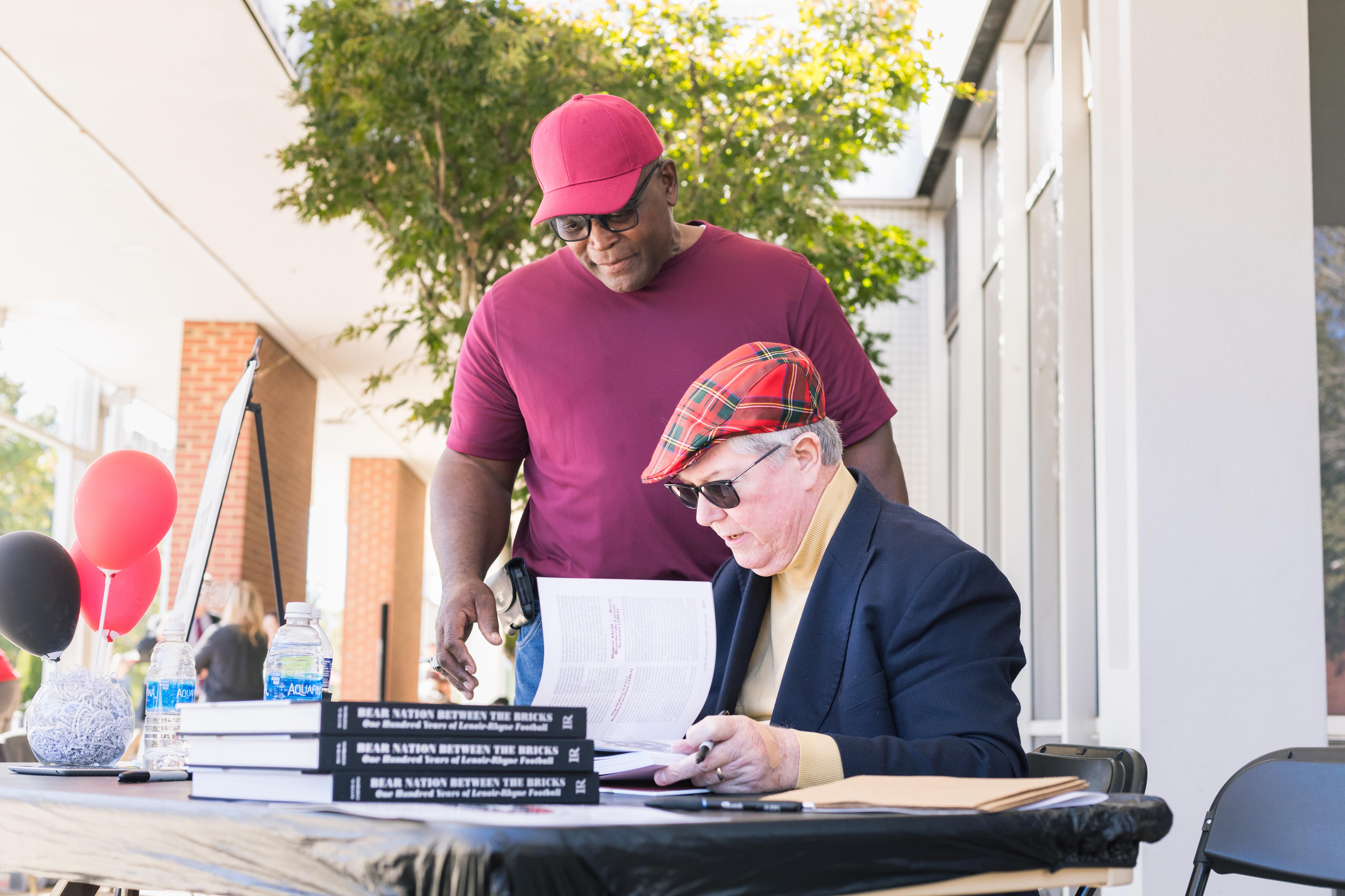 David Stephens, right, signs a copy of his book for a fellow LR alum