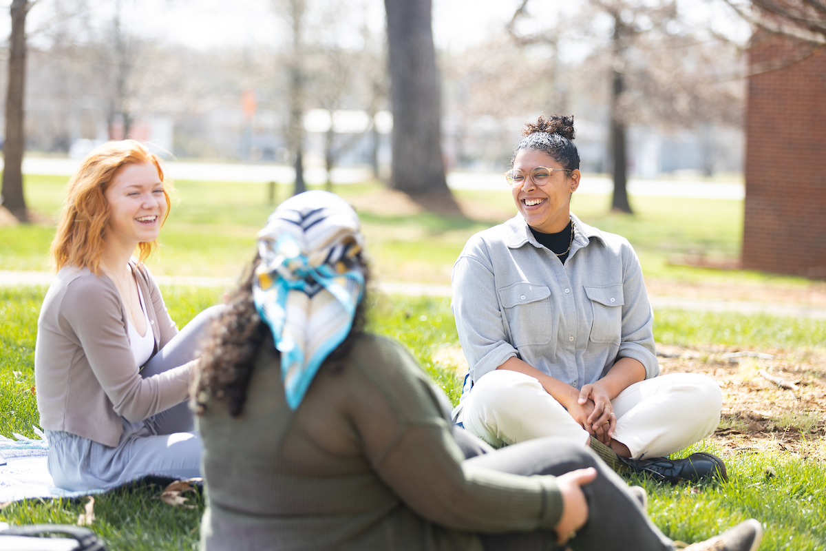 D.M. Spratley, right, sits with two students outside during a class