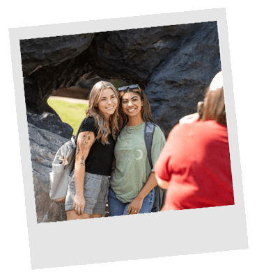 Two students taking photo in front of The Charge sculpture on campus