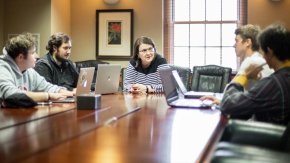 Student investors talk with professor seated around a conference table