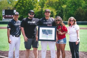 Five people stand together on baseball field