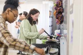 Students laddle soup into bowls inside