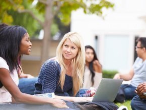 Group of students sitting outside on lawn on campus