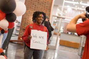 Student holds a sign reading 'We are community'