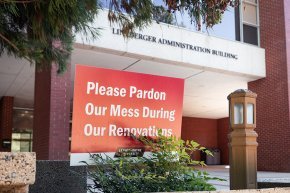 A sign reading "please pardon our mess during our renovations" stands in front of Lineberger Administration Building.