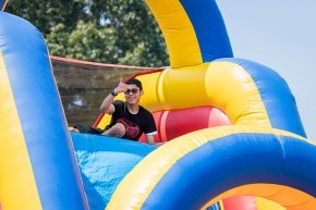 A student gives the thumbs-up from the top of a colorful inflatable slide