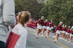 Spirit team marches in the 2023 homecoming parade with band visible behind them