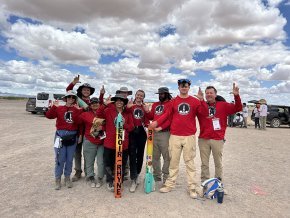 The Aerobears team pose with their 2024 rocket and show the LR hand sign in the New Mexico desert