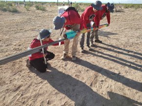 Four members of the Aerobears team load their rocket onto the launch rail in the desert