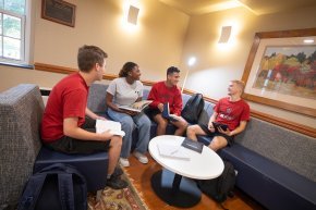 Four students chat while studying indoors