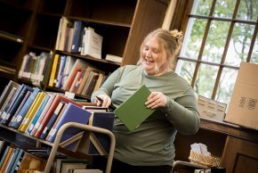 Lillian Cummines files books on a cart in Rudisill Library