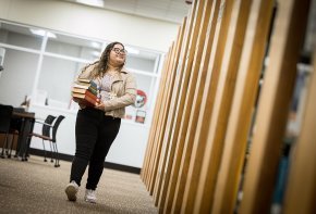 Lizbeth Santibanez carries a stack of books into the shelves in Rudisill Library