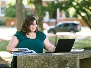 Tera Peña working on a computer in the quad.