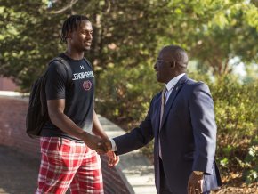 Avery Staley, right, shakes hands with a student, left, outside on campus.