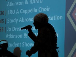 A performer stands on stage with a mic