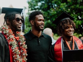 Two graduates of the Class of 2022 pose for photos outside after commencement ceremony