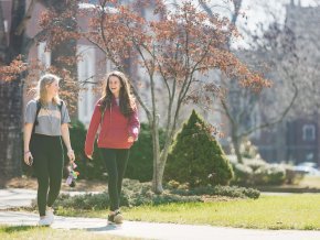 Two female students walk outside on campus