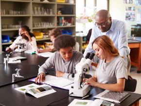 A teacher talks with students in classroom lab