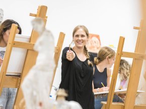 Claire Pope stands in an art classroom with students around her