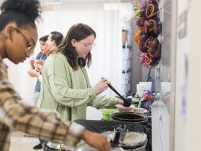 Students laddle soup into bowls inside