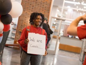 Student holds a sign reading 'We are community'