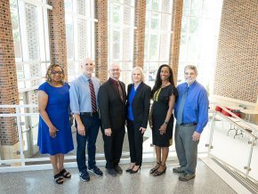 Six members of the grant writing team for the Noyce scholarship program stand in the George Hall lobby