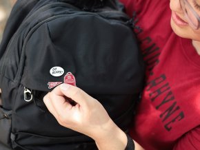 Student displays three enamel pins on a backpack in closeup