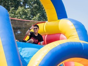 A student gives the thumbs-up from the top of a colorful inflatable slide