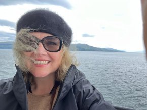 Laura Hope Gill on a boat with Scottish coastline in the background