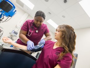 Two nursing students practice with a blood pressure cuff