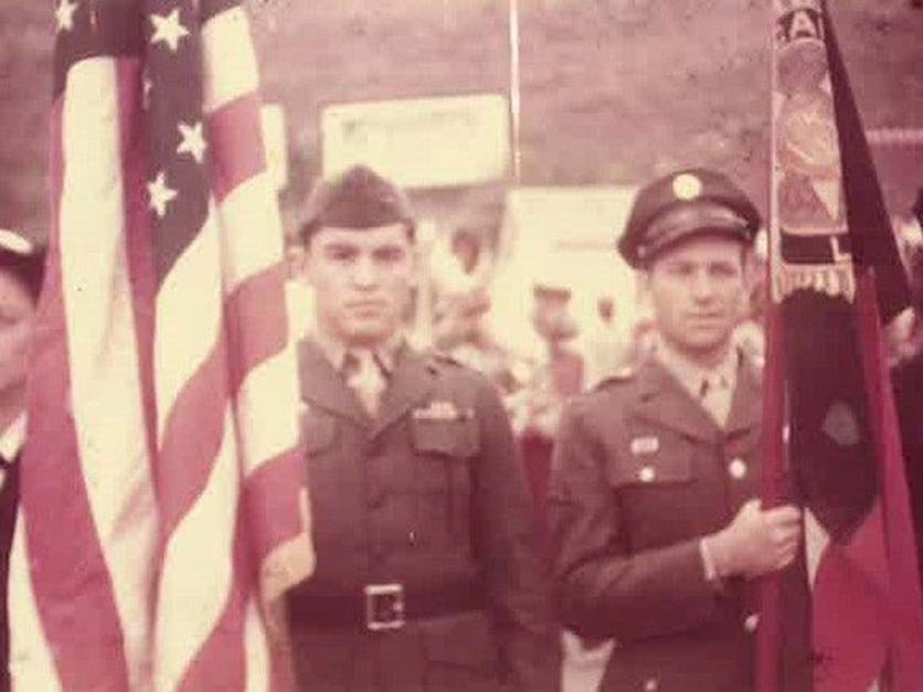 Hanley Painter in his uniform with an American flag walking in a parade.