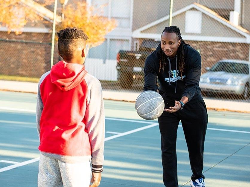 Jamal Stroud playing basketball with a child.