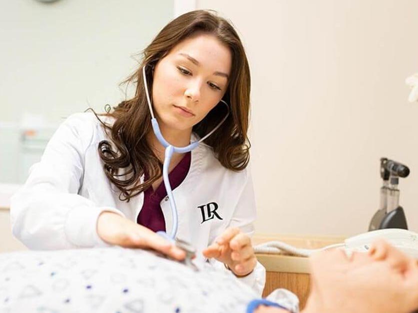 Nursing student practices checking a patient's breathing with a stethoscope