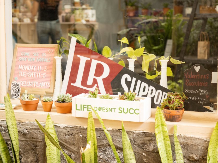 A shop window features an LR supporter flag.