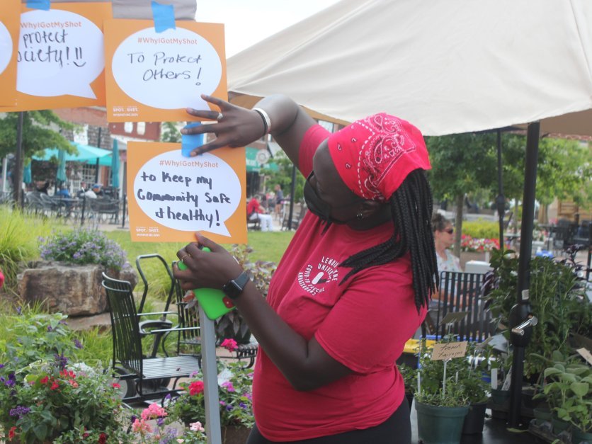 A masked student tapes a sign to a post.