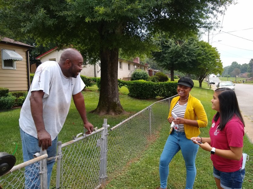 Two students, right, talk to a member of the community outdoors.