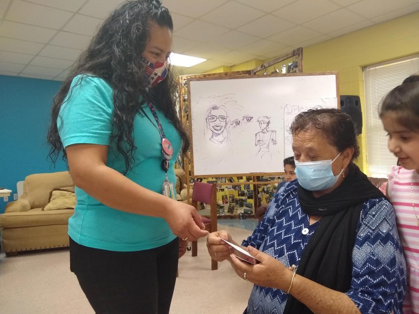 A masked student, left, speaks with a masked woman indoors.