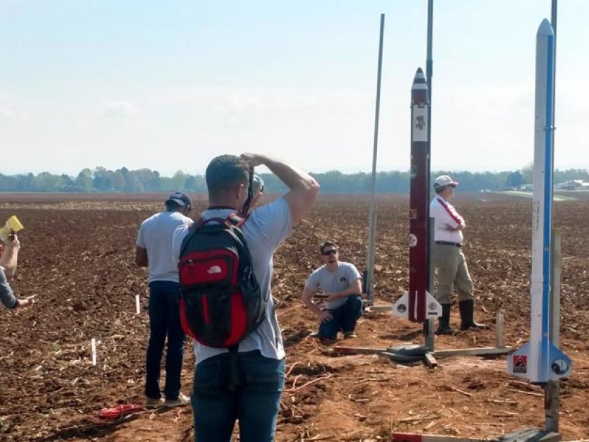 Spectators watch a rocket launch in a corn field