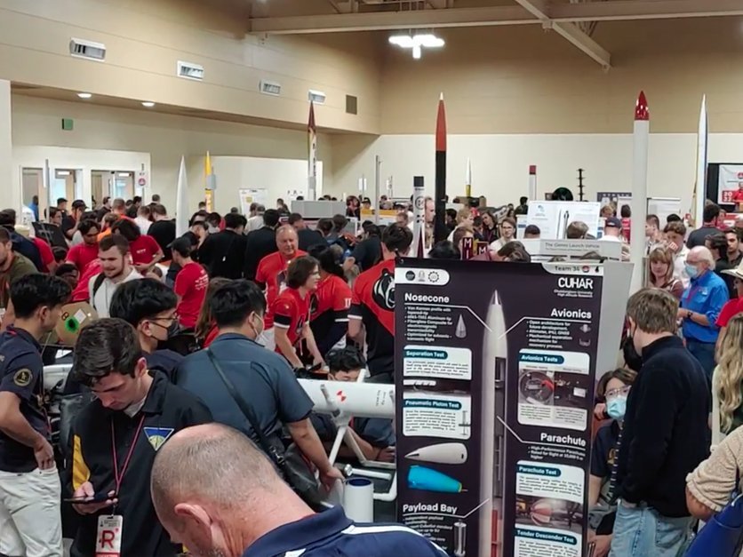 Students gather with rocket exhibits in exhibit hall