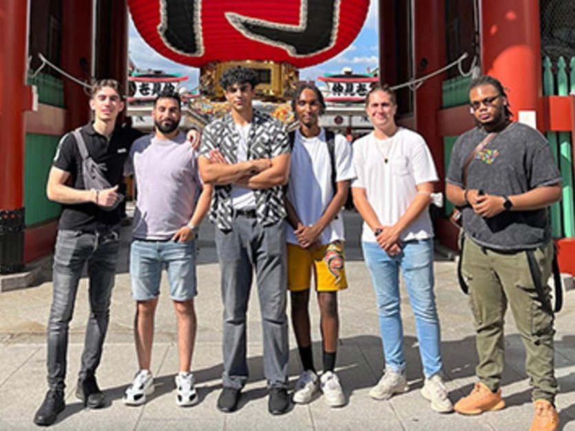 Jalen poses with group of friends in front of tourism landmark